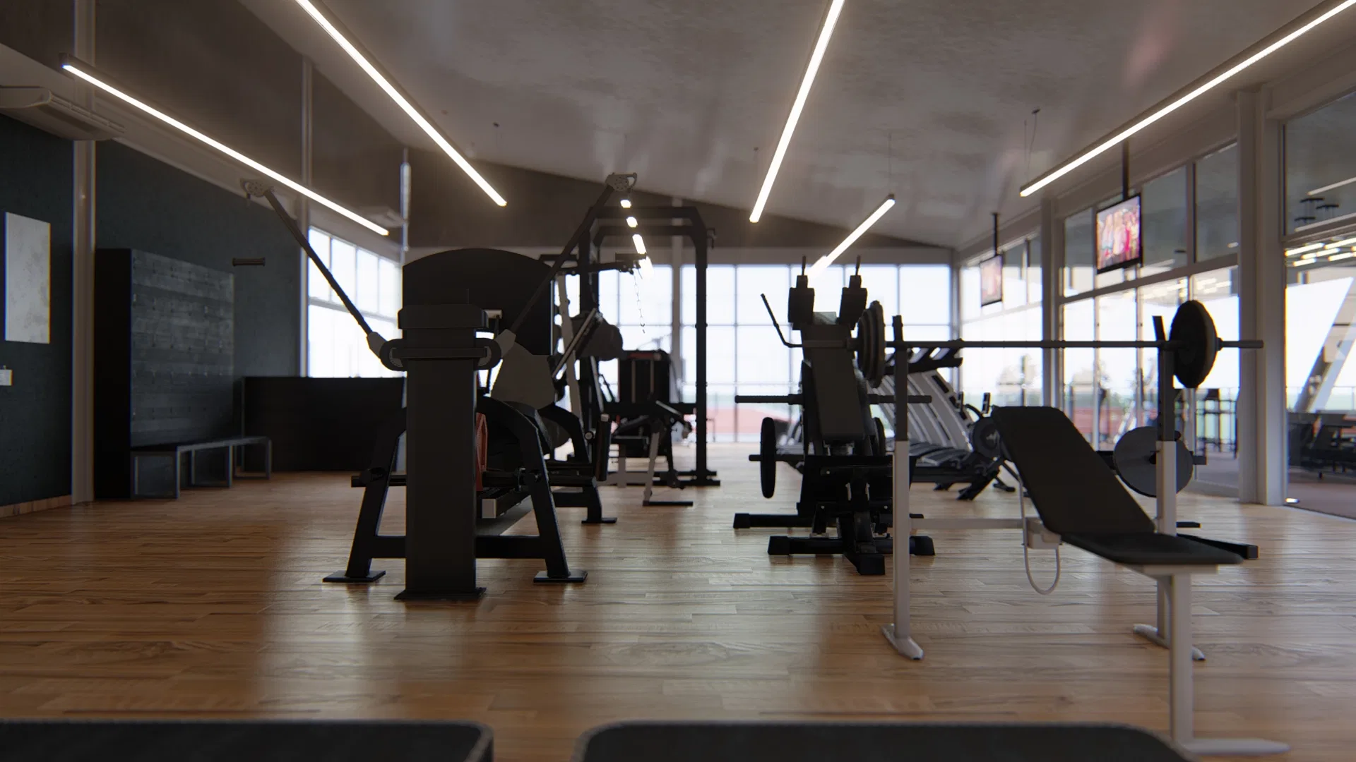 Sala de peso livre em luz baixa, com máquinas e bancos alinhados, banco inclinado em primeiro plano, piso de madeira e amplas janelas ao fundo