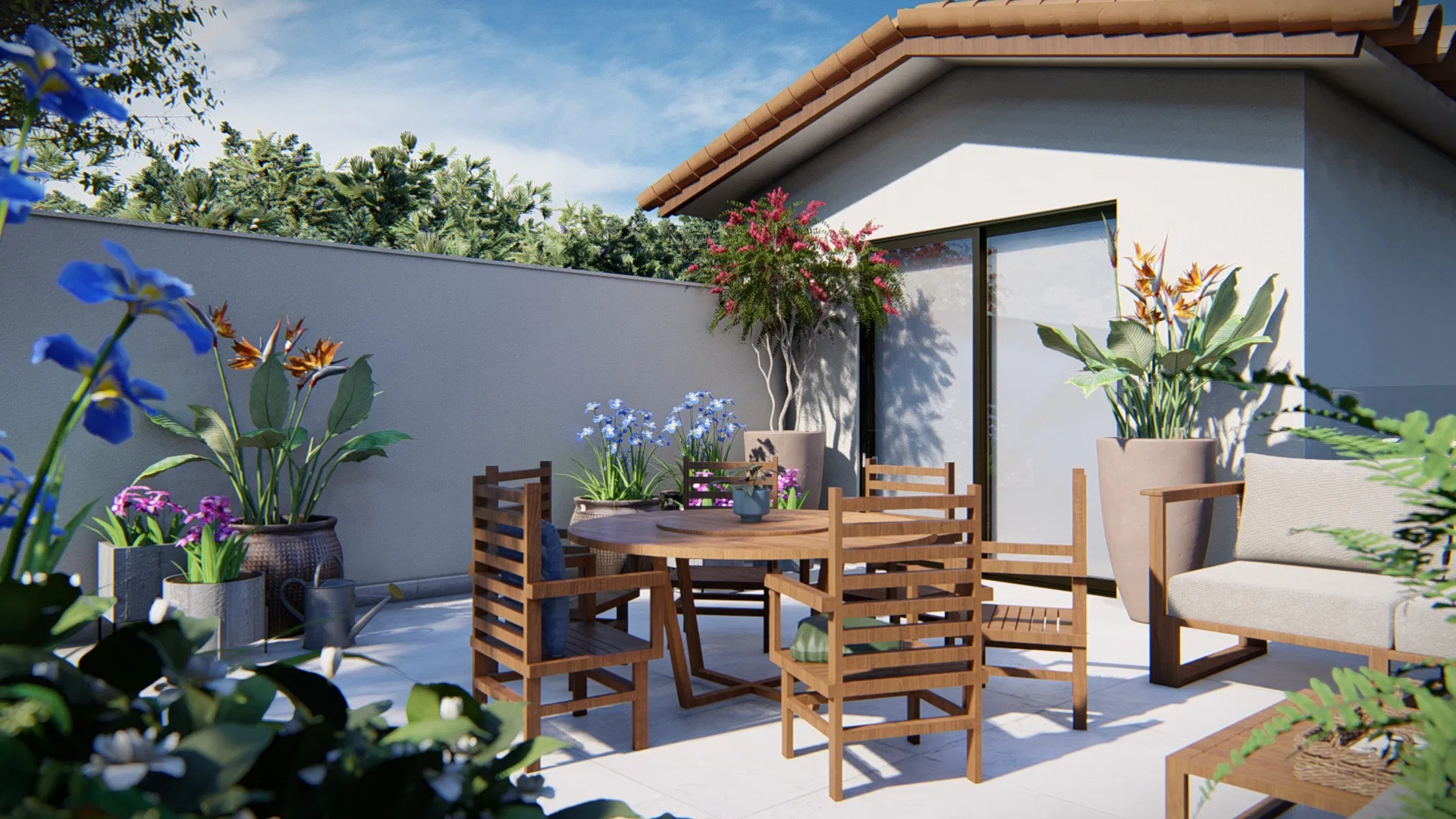Terraço com mesa redonda de madeira e cadeiras, vasos de íris azuis e estrelícias, diante de uma área coberta com portas de vidro sob céu azul.
