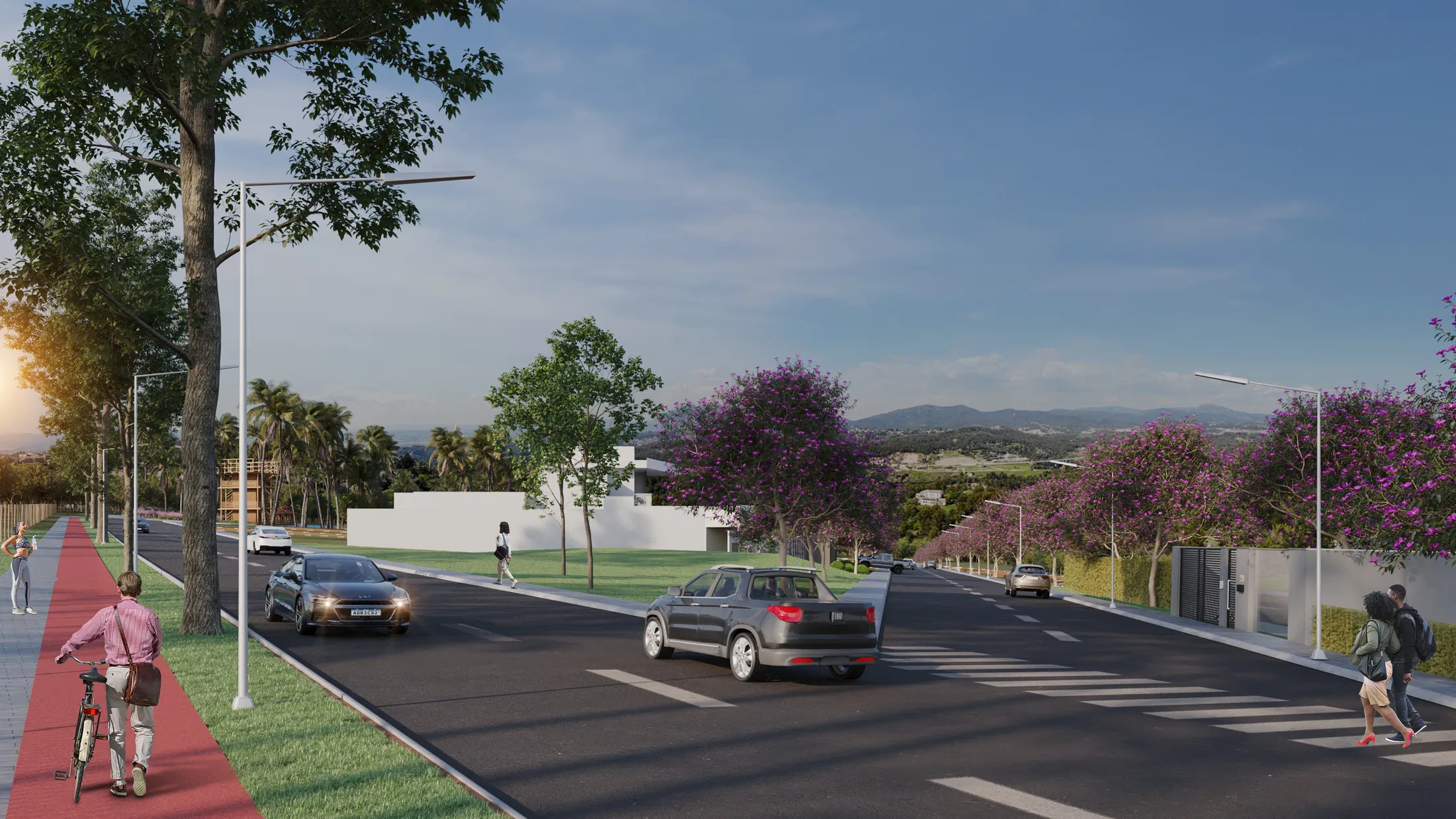 Avenida com ciclovia vermelha ladeada por árvores de flores roxas, postes e carros, com montanhas ao fundo ao entardecer