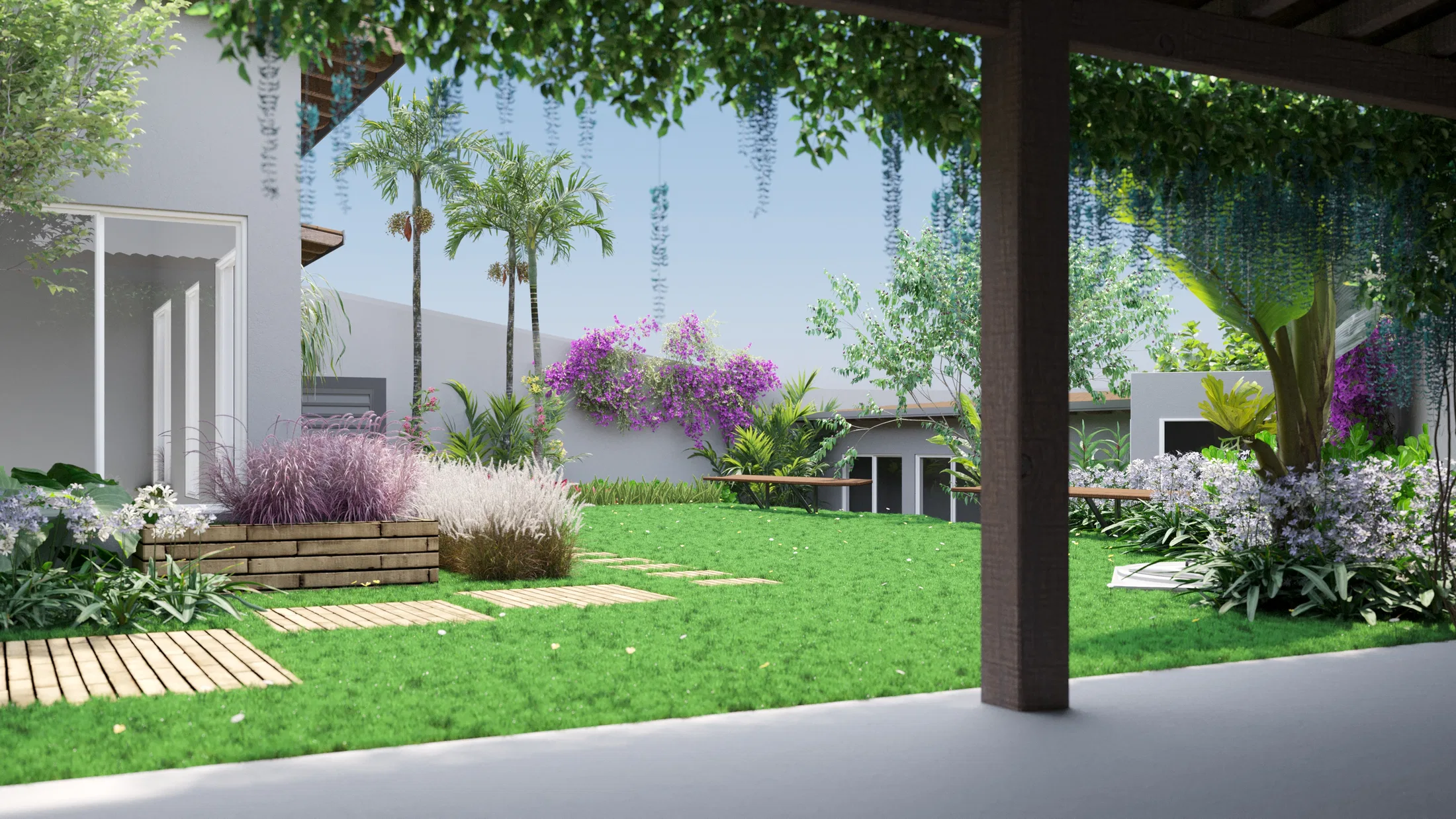 Vista sob pérgola para o jardim, com palmeiras, buganvília sobre o muro, gramíneas em floreira de madeira e caminho de deck no gramado.