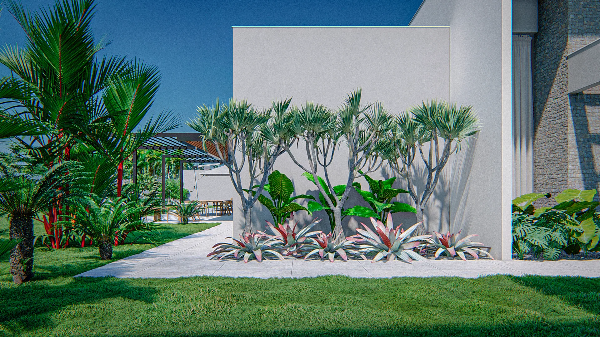 Canto de jardim com dracenas ramificadas e bromélias avermelhadas ao pé de parede branca, palmeiras ao lado e pergolado com estar ao fundo
