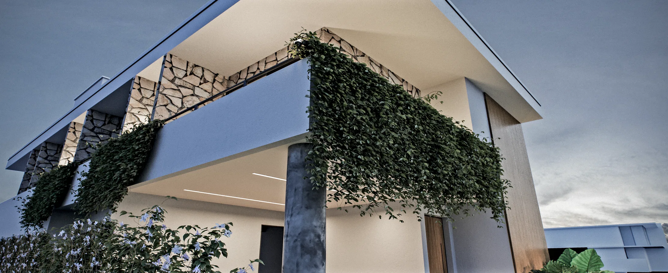 Detalhe do volume superior com revestimento de pedra e uma varanda em balanço envolta por vegetação pendente densa ao entardecer.