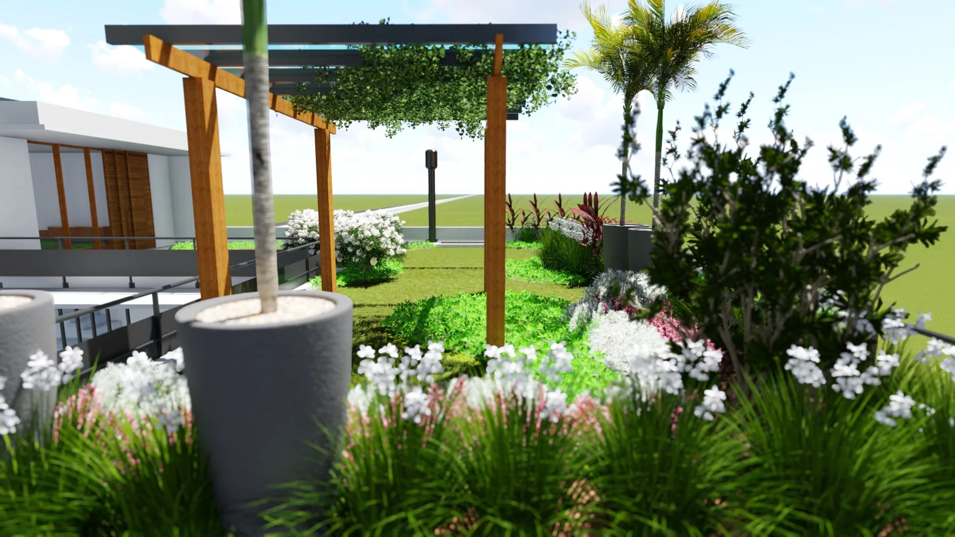 Jardim com pergolado de madeira, árvore recém-plantada em vaso de concreto e canteiros floridos de branco entre gramíneas
