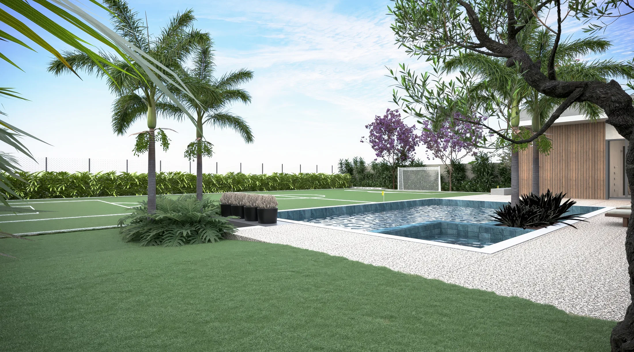 Quintal com piscina de pastilha azul e deque de seixos, quadra esportiva em grama sintética, coqueiros e jacarandá florido ao fundo