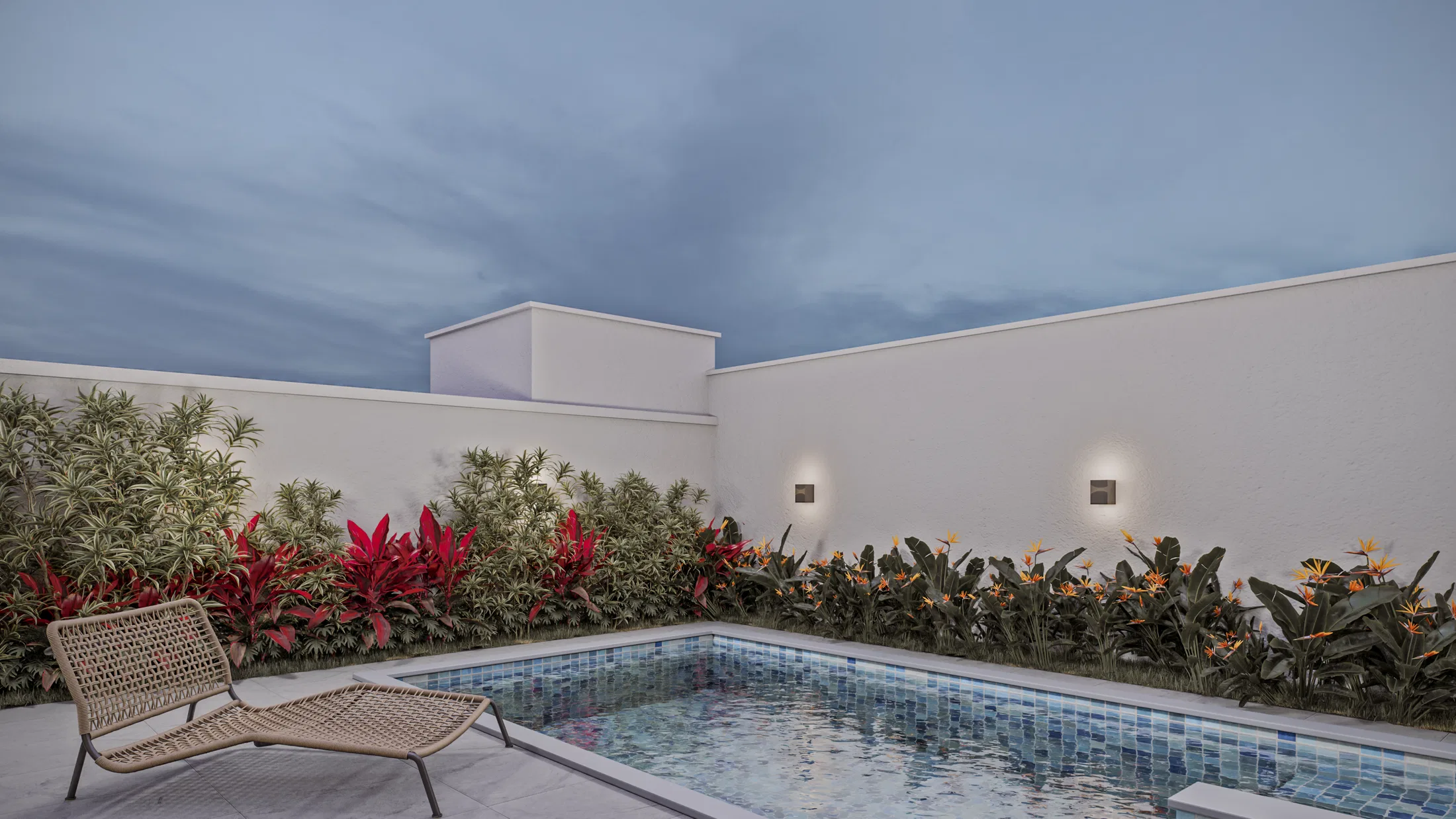 Piscina de fundos com pastilhas azuis, espreguiçadeira e canteiro de folhagens vermelhas e aves-do-paraíso junto ao muro