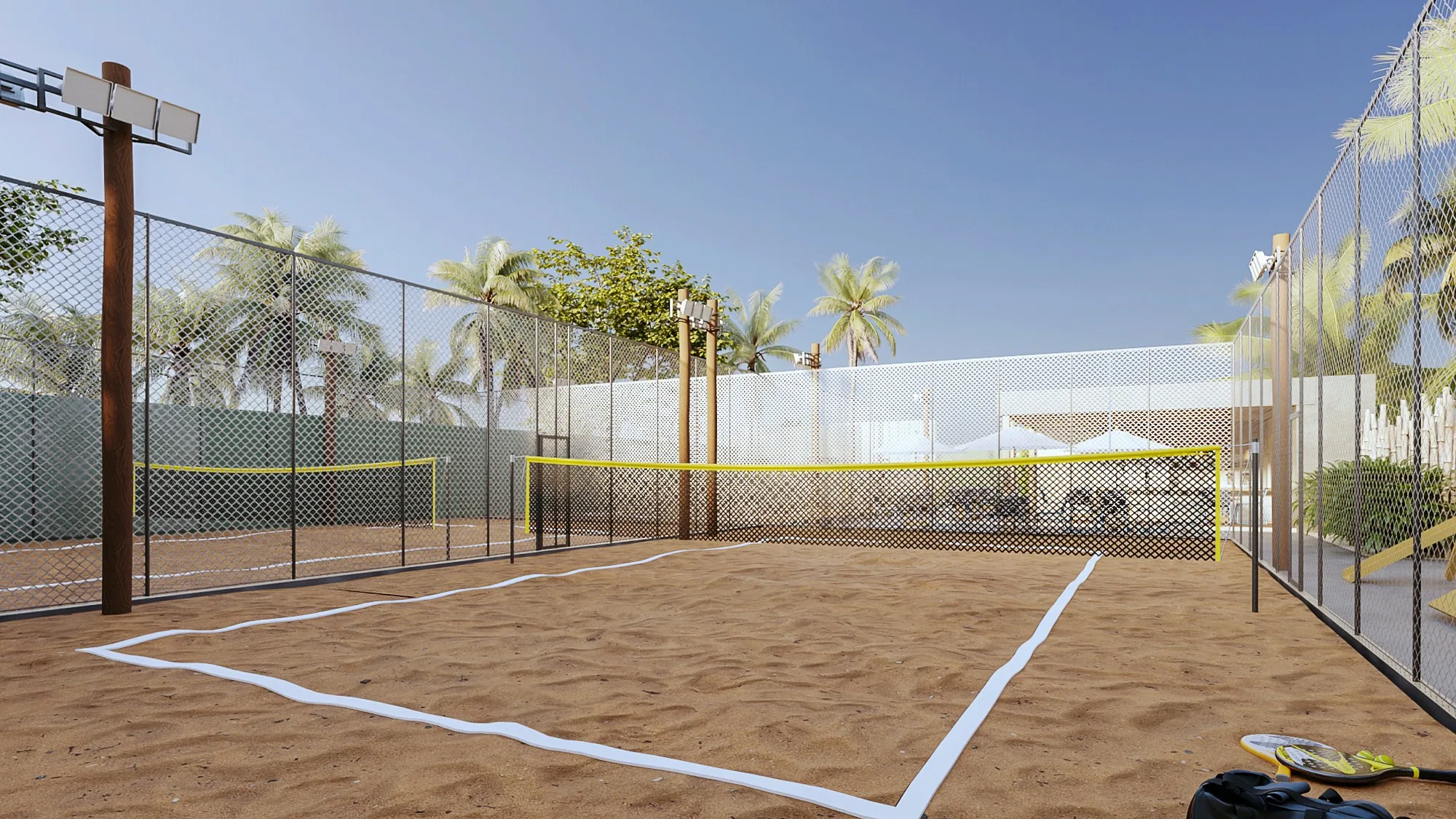 Quadra individual de beach tennis com rede de fita amarela, linhas brancas na areia e raquetes no canto, cercada por telamento e coqueiros