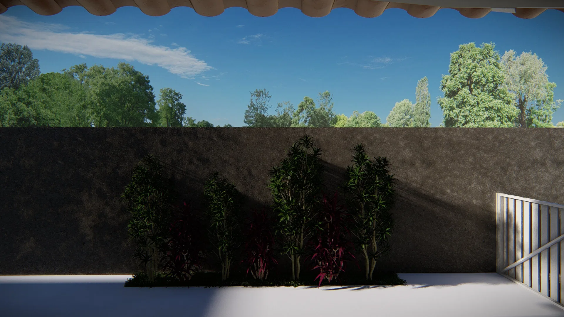 Muro escuro de divisa com faixa estreita de gramíneas e uma folhagem magenta, visto sob o beiral de telhas, com copas de árvores ao fundo